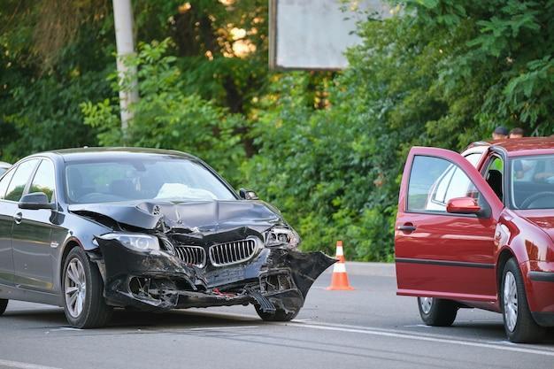 Damaged in heavy car accident vehicles after collision on city street crash site. Road safety and insurance concept.